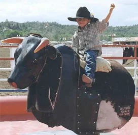 Young cowboy riding mechanical bull