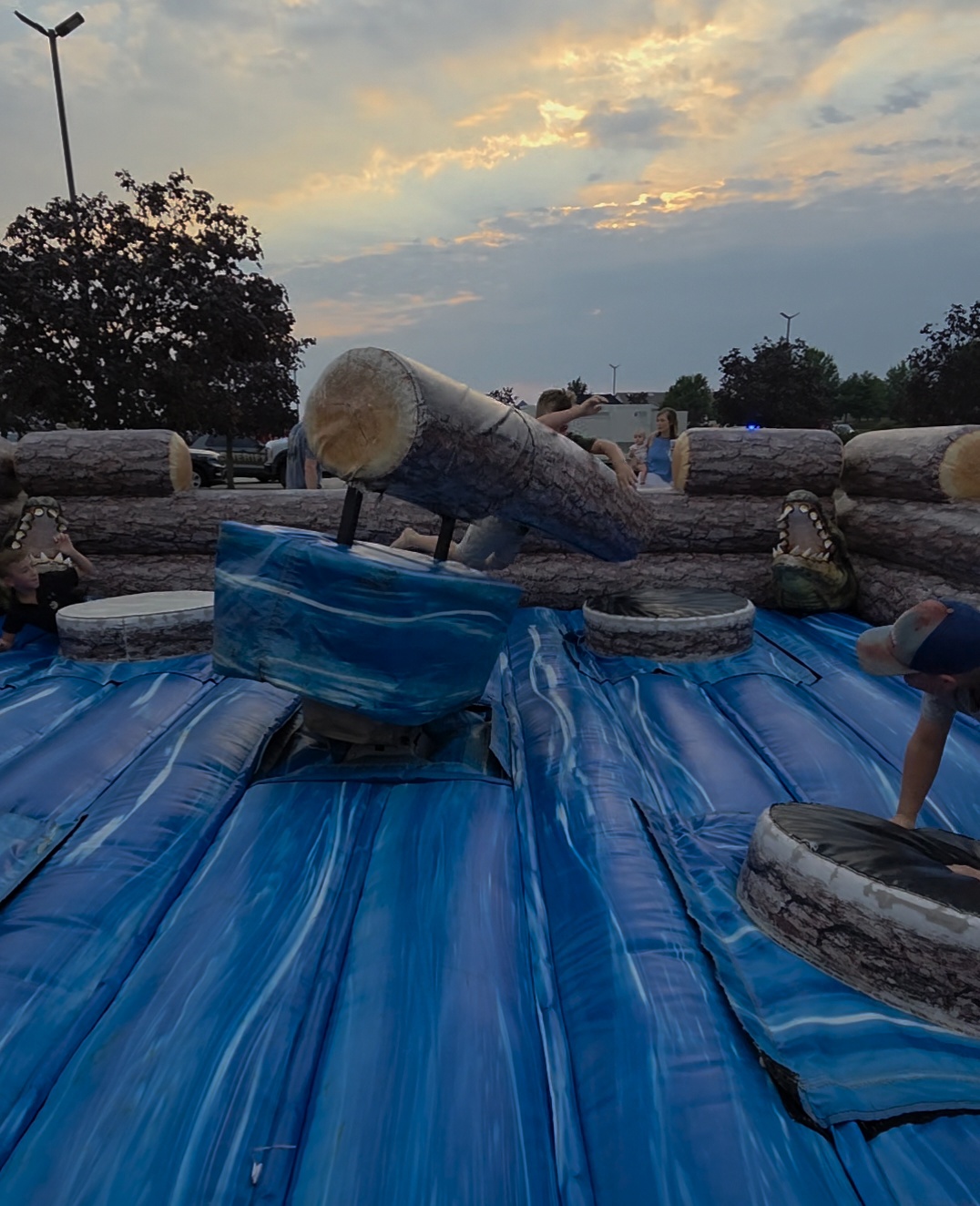 Kids and adults on the inflatable log jam wipeout ride at sunset