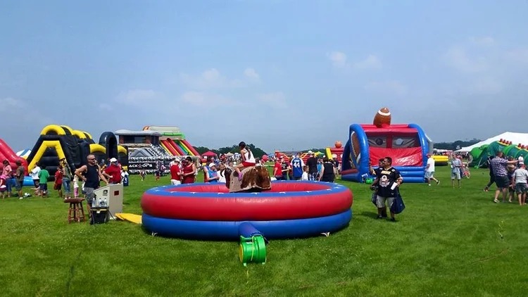 Field festival with bounce houses and mechanical bull