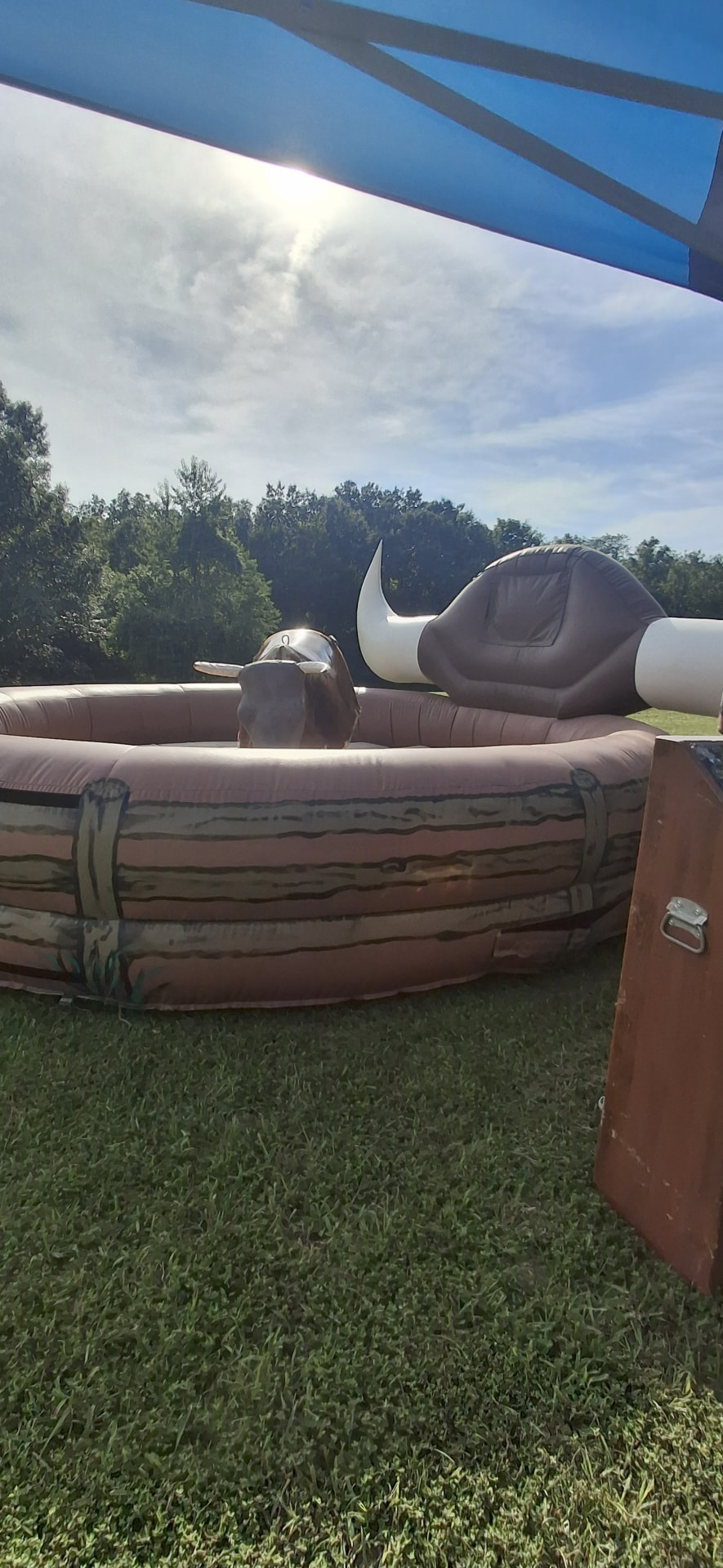 Mechanical bull with shade tent set up in a grassy field